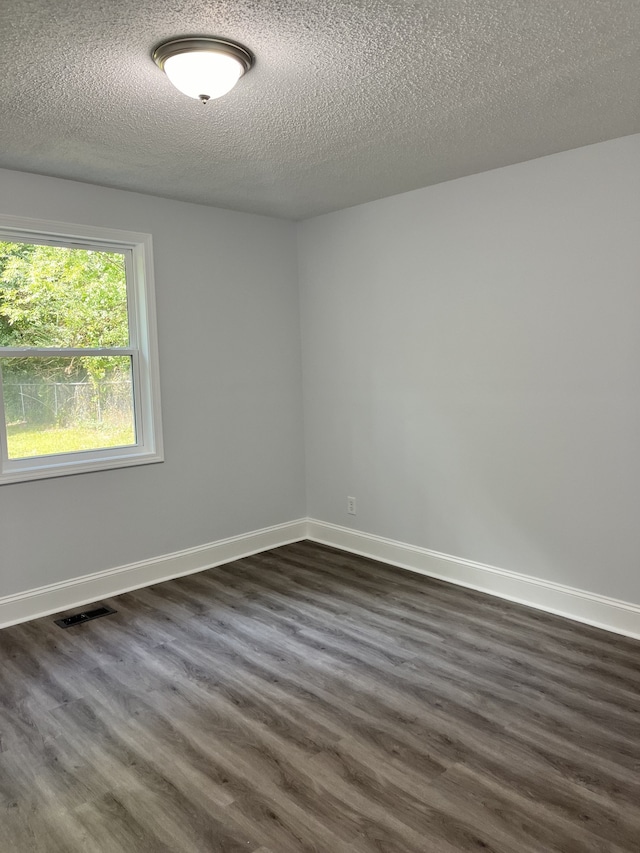 unfurnished room with dark wood-type flooring and a textured ceiling