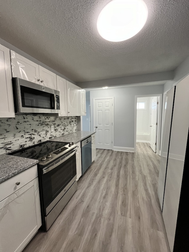 kitchen featuring appliances with stainless steel finishes, light hardwood / wood-style flooring, white cabinets, and tasteful backsplash