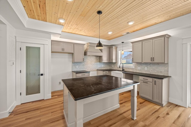 kitchen with a center island, light hardwood / wood-style floors, crown molding, and wooden ceiling