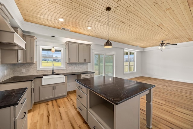 kitchen with ceiling fan, a center island, sink, light hardwood / wood-style floors, and decorative light fixtures