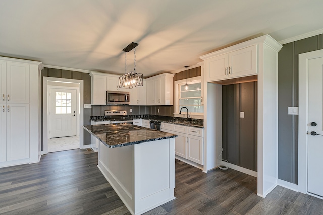 kitchen with dark wood-type flooring, appliances with stainless steel finishes, decorative light fixtures, and white cabinetry