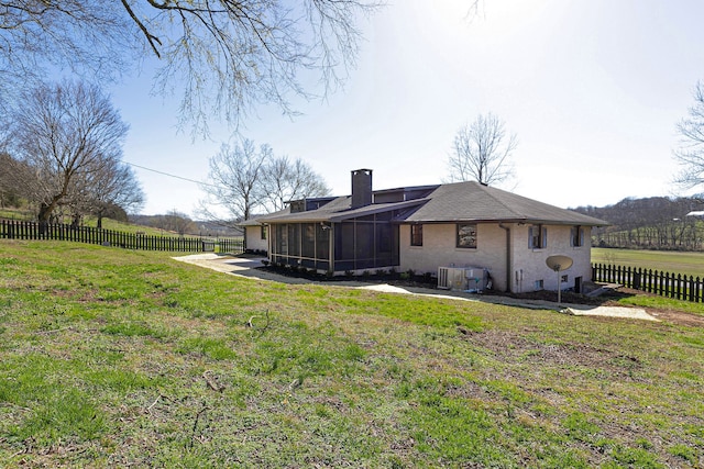 back of house with a sunroom and a lawn