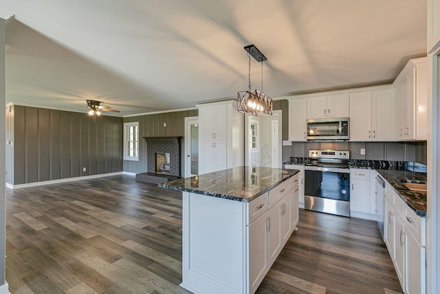 kitchen featuring dark wood-type flooring, white cabinets, stainless steel appliances, and a center island