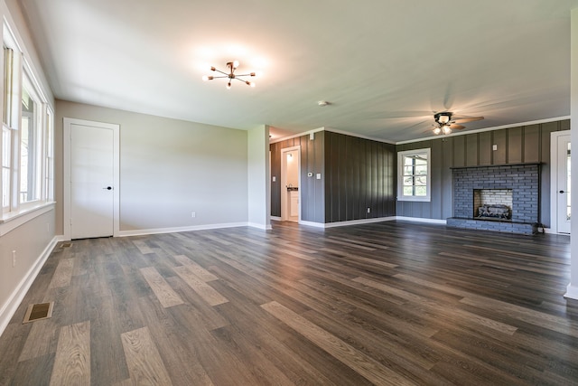 unfurnished living room with ceiling fan, a fireplace, wooden walls, and dark hardwood / wood-style floors