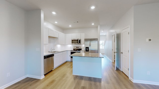 kitchen with a kitchen island, appliances with stainless steel finishes, light wood-type flooring, and white cabinets