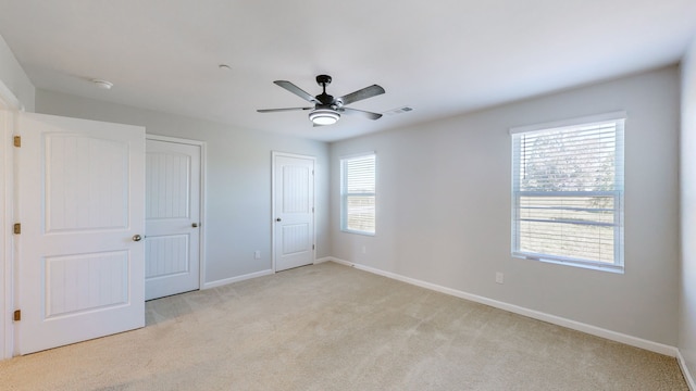 unfurnished bedroom with light carpet, multiple windows, and ceiling fan