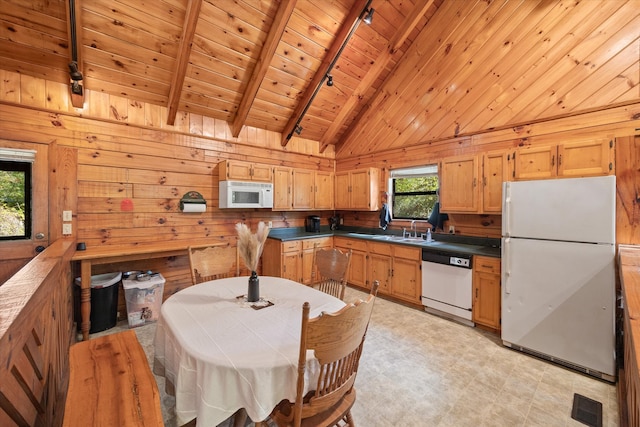 kitchen with white appliances, wooden ceiling, beamed ceiling, wooden walls, and track lighting