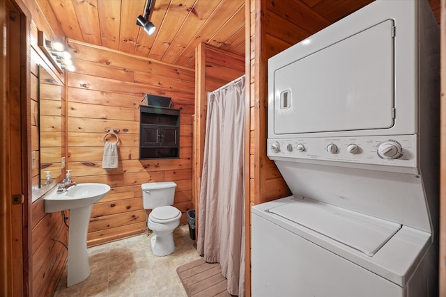 bathroom featuring stacked washing maching and dryer, walk in shower, wooden ceiling, toilet, and wooden walls