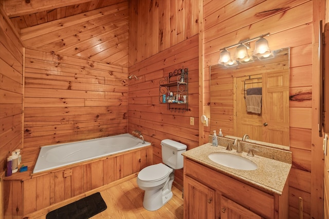 bathroom featuring wood-type flooring, vanity, toilet, wooden walls, and a bathtub