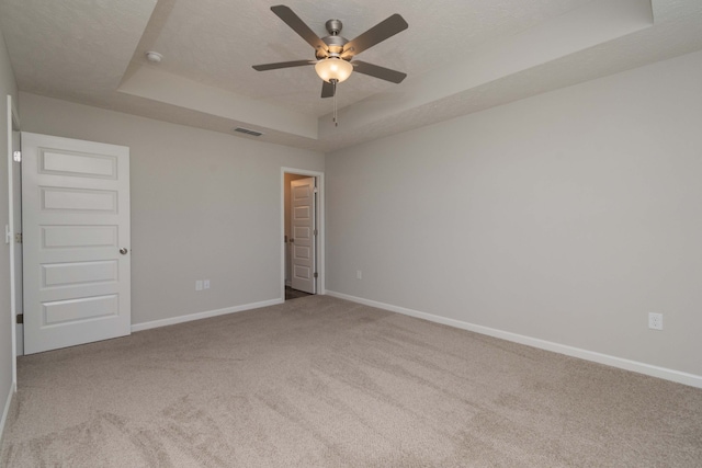 carpeted empty room with ceiling fan, a textured ceiling, and a raised ceiling