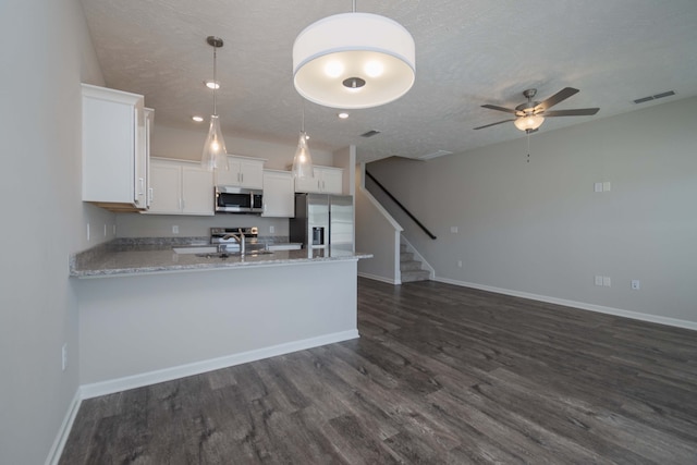 kitchen with a textured ceiling, white cabinetry, stainless steel appliances, decorative light fixtures, and dark hardwood / wood-style floors