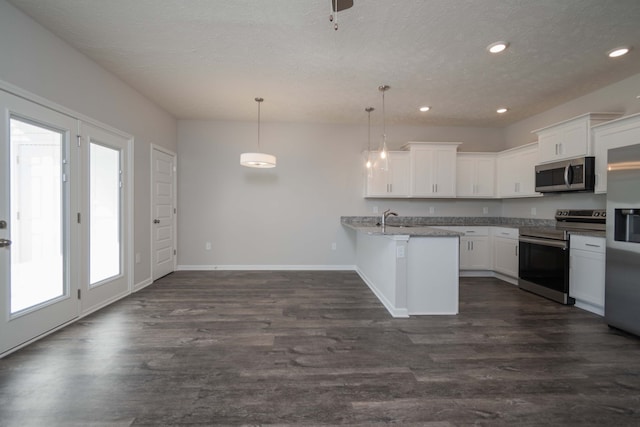 kitchen with kitchen peninsula, white cabinets, pendant lighting, appliances with stainless steel finishes, and dark hardwood / wood-style flooring