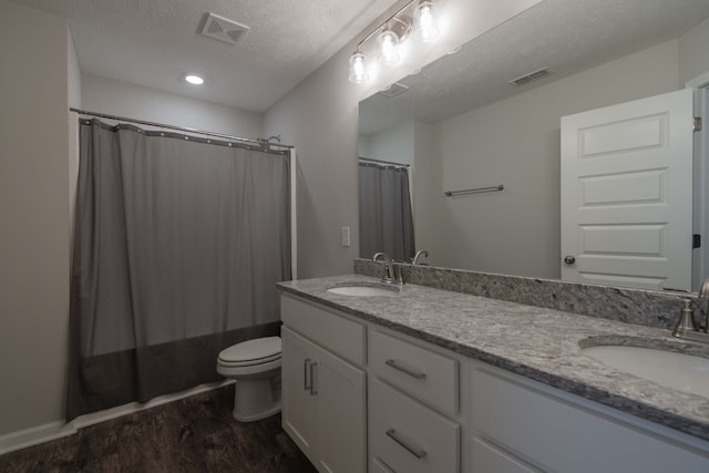 full bathroom featuring vanity, hardwood / wood-style floors, toilet, and a textured ceiling