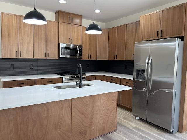 kitchen featuring sink, hanging light fixtures, decorative backsplash, appliances with stainless steel finishes, and light hardwood / wood-style floors