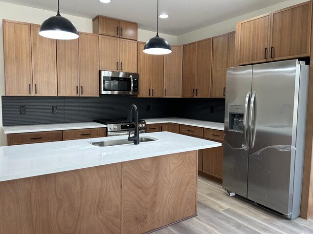 kitchen with tasteful backsplash, sink, stainless steel appliances, and decorative light fixtures