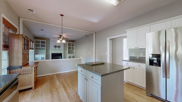 kitchen featuring dark stone countertops, a center island, light wood-type flooring, white cabinetry, and appliances with stainless steel finishes