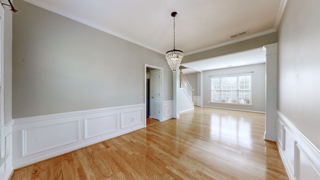 unfurnished dining area featuring light hardwood / wood-style floors, crown molding, and a chandelier