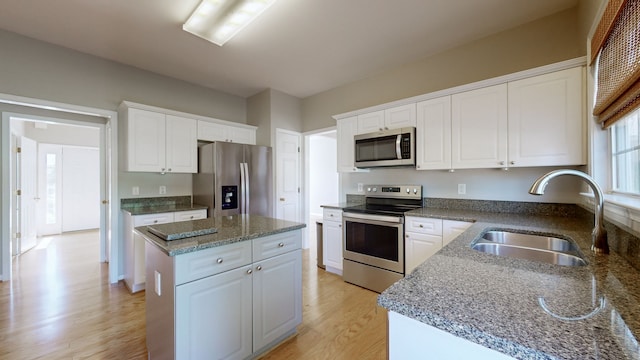 kitchen with a kitchen island, sink, white cabinets, light wood-type flooring, and appliances with stainless steel finishes