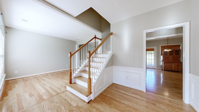 staircase featuring wood-type flooring and an inviting chandelier