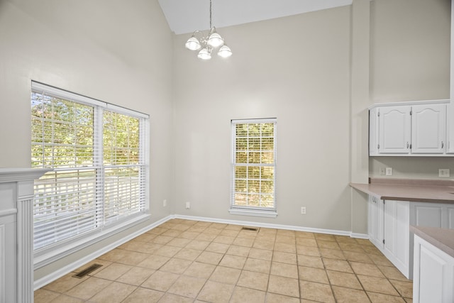 unfurnished dining area featuring high vaulted ceiling, light tile patterned flooring, and a chandelier