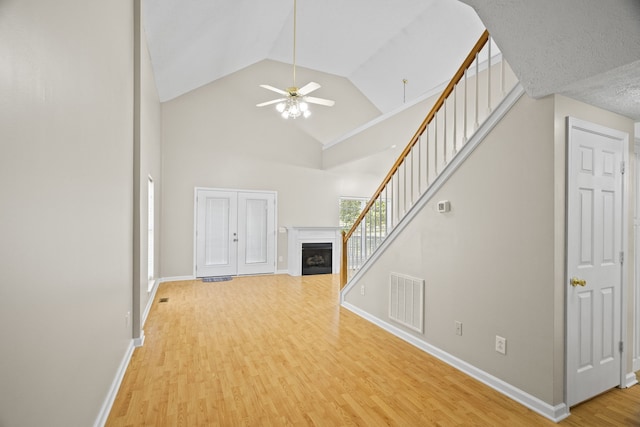 unfurnished living room with hardwood / wood-style flooring, high vaulted ceiling, and ceiling fan