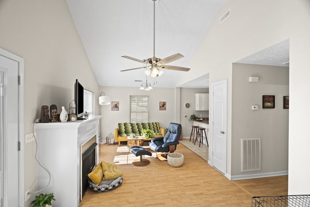 sitting room featuring ceiling fan, high vaulted ceiling, a textured ceiling, and light wood-type flooring