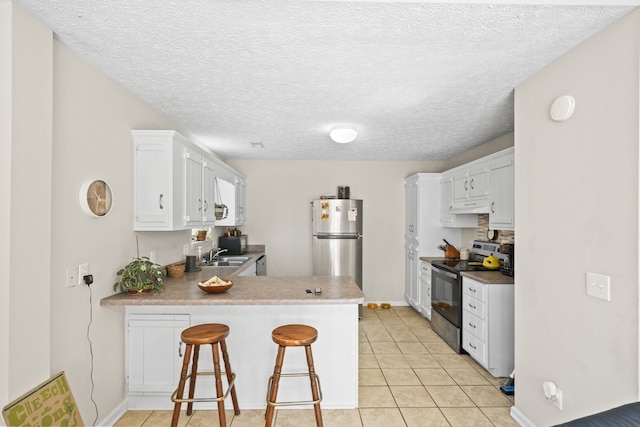 kitchen featuring appliances with stainless steel finishes, a breakfast bar area, kitchen peninsula, and white cabinets