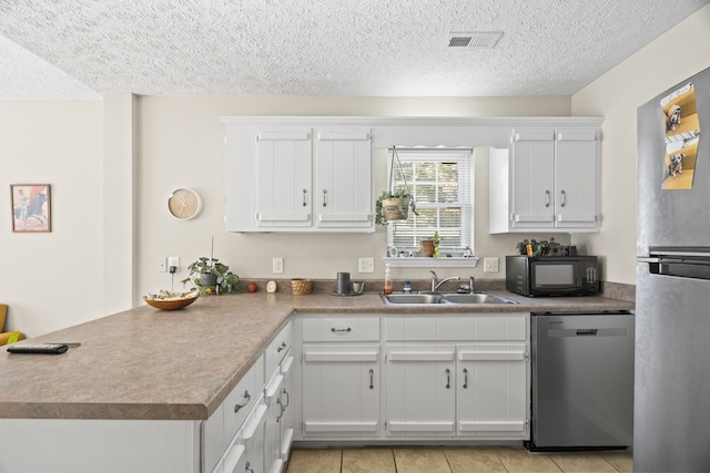 kitchen featuring appliances with stainless steel finishes, white cabinets, sink, and a textured ceiling