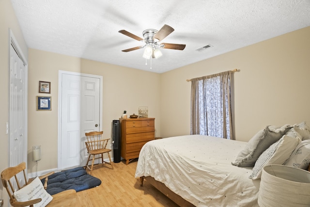 bedroom with ceiling fan, a textured ceiling, and light hardwood / wood-style flooring