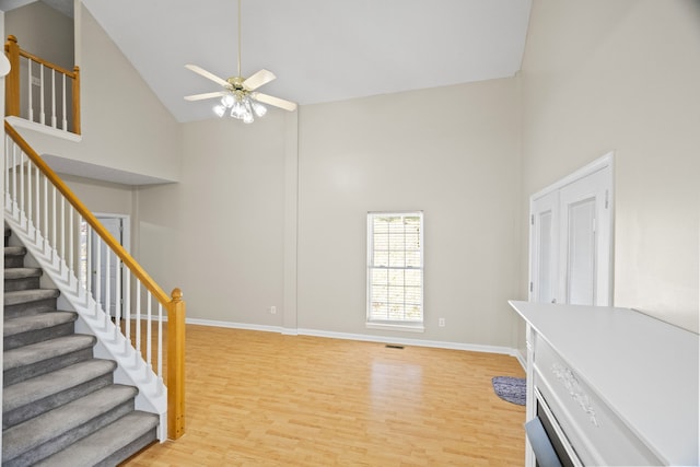 living room featuring light hardwood / wood-style floors, high vaulted ceiling, and ceiling fan