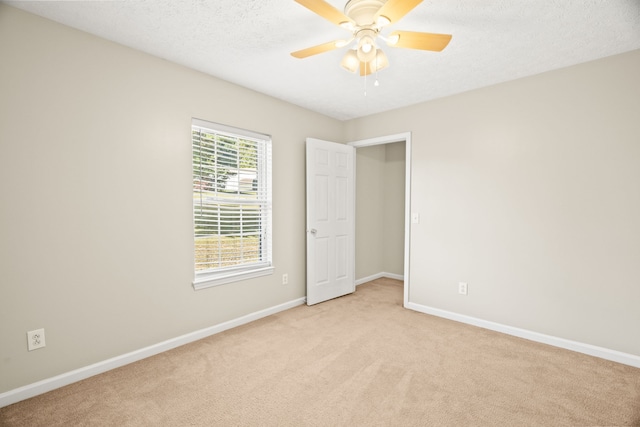 carpeted empty room featuring ceiling fan and a textured ceiling