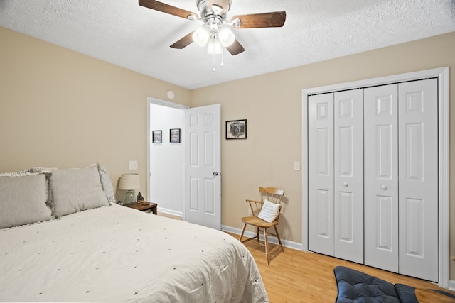 bedroom featuring a closet, hardwood / wood-style floors, a textured ceiling, and ceiling fan