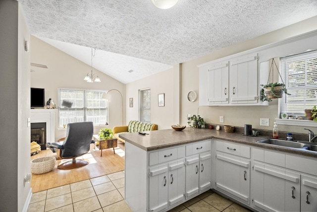 kitchen featuring sink, white cabinetry, lofted ceiling, decorative light fixtures, and light tile patterned floors