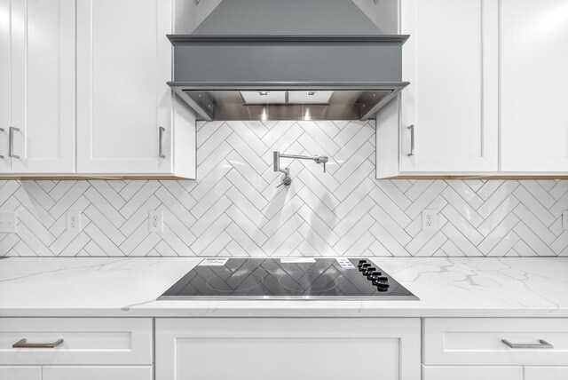 kitchen with light stone counters, decorative backsplash, black electric cooktop, and white cabinets