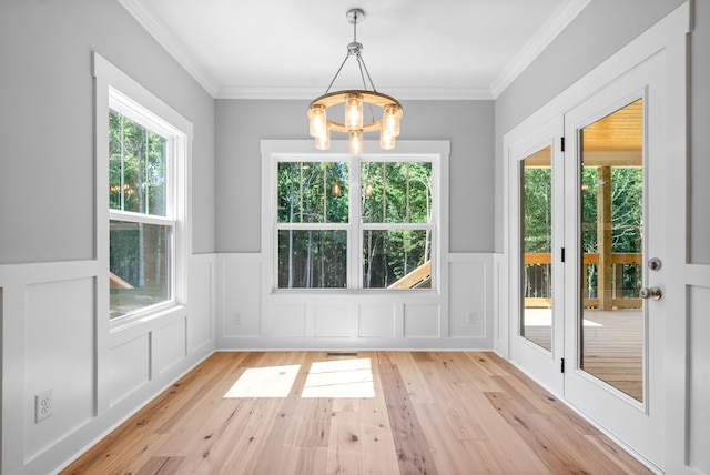 unfurnished dining area featuring ornamental molding, a wealth of natural light, and light wood-type flooring