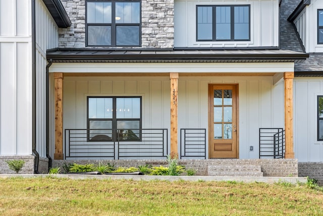 doorway to property featuring covered porch and a lawn