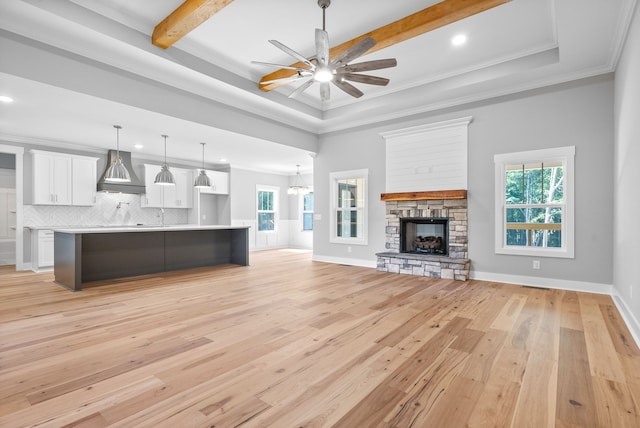 unfurnished living room featuring light hardwood / wood-style floors, a fireplace, a healthy amount of sunlight, and ceiling fan with notable chandelier