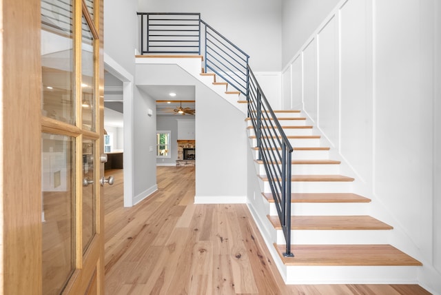 staircase featuring a stone fireplace and hardwood / wood-style floors