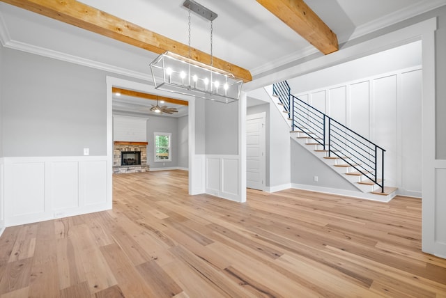 unfurnished living room with beam ceiling, ornamental molding, light wood-type flooring, a fireplace, and ceiling fan