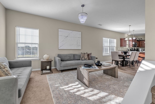 living room with light carpet, a notable chandelier, and a wealth of natural light