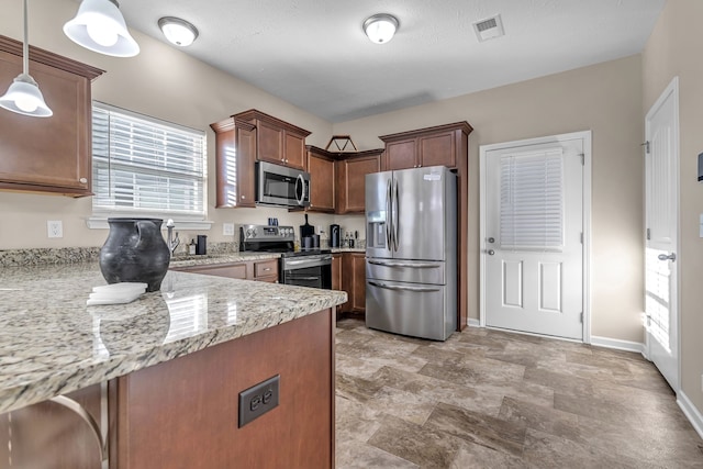 kitchen featuring appliances with stainless steel finishes, kitchen peninsula, decorative light fixtures, and light stone counters