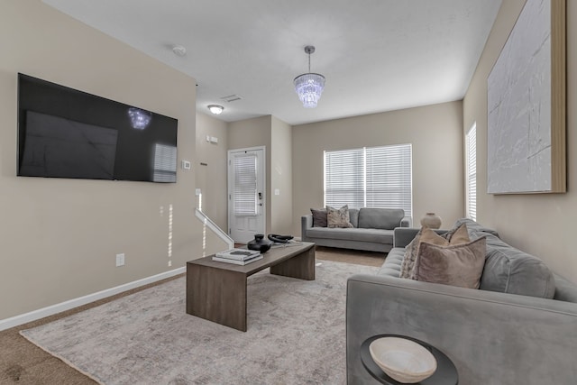 carpeted living room with an inviting chandelier