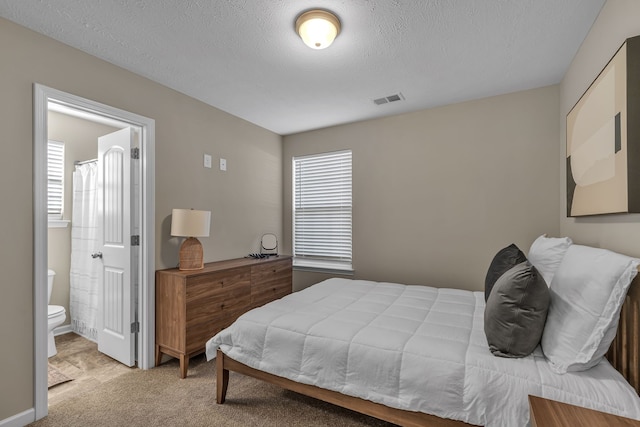 carpeted bedroom with a textured ceiling and ensuite bath