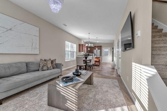 carpeted living room with an inviting chandelier