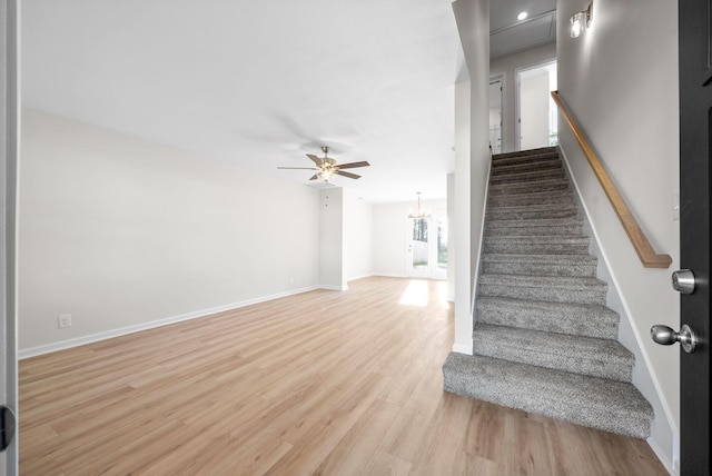 stairway with hardwood / wood-style floors and ceiling fan