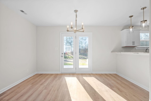 unfurnished dining area with light hardwood / wood-style floors and an inviting chandelier