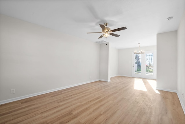 spare room with ceiling fan with notable chandelier and light hardwood / wood-style flooring