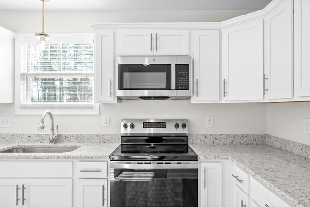 kitchen with pendant lighting, white cabinets, sink, light stone countertops, and appliances with stainless steel finishes