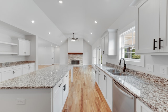 kitchen with stainless steel dishwasher, lofted ceiling, sink, and white cabinets