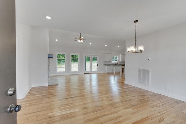 unfurnished living room featuring light hardwood / wood-style floors, sink, and ceiling fan with notable chandelier